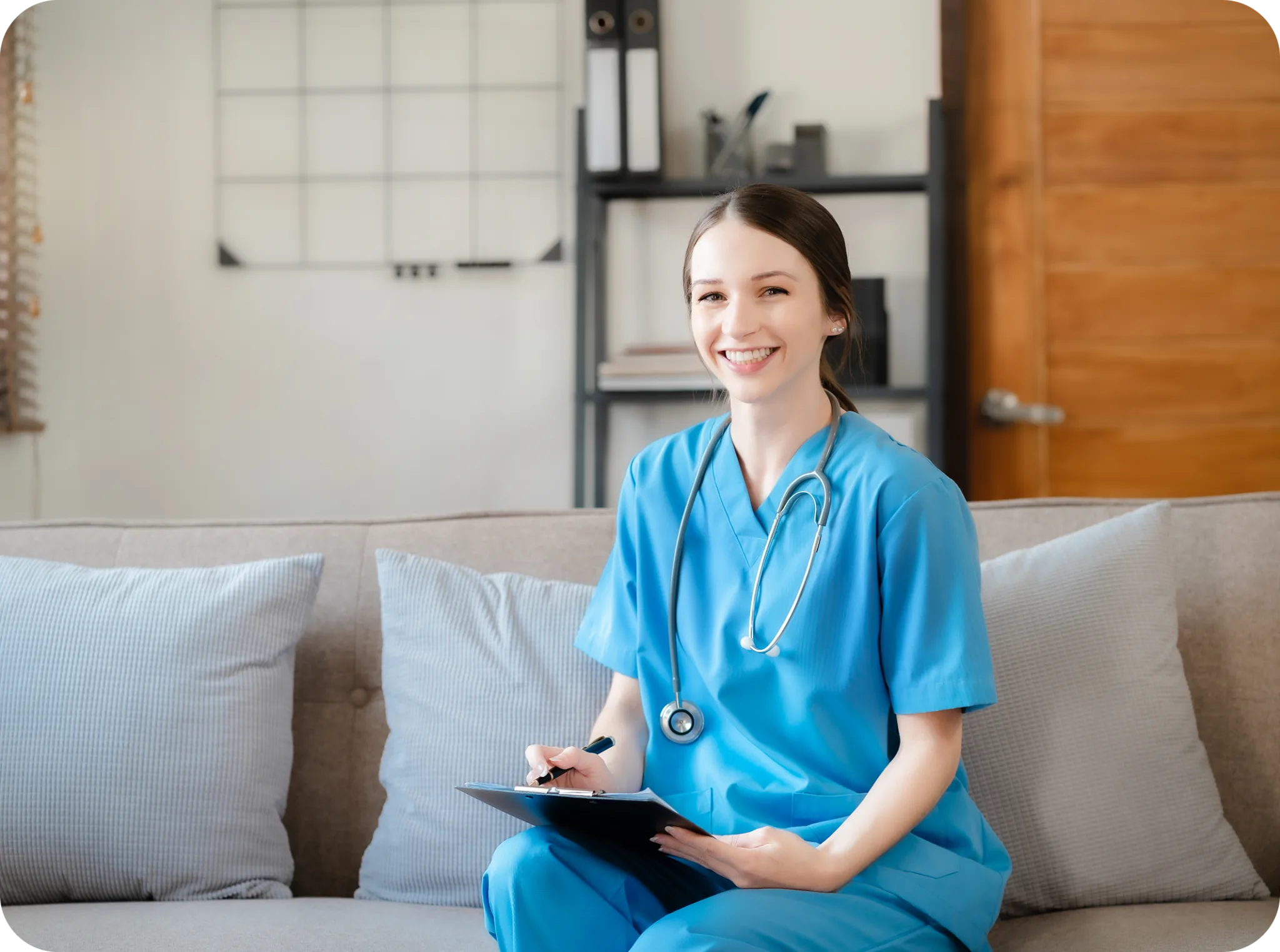 A care coordinator in scrubs sitting with a clipboard in a client home