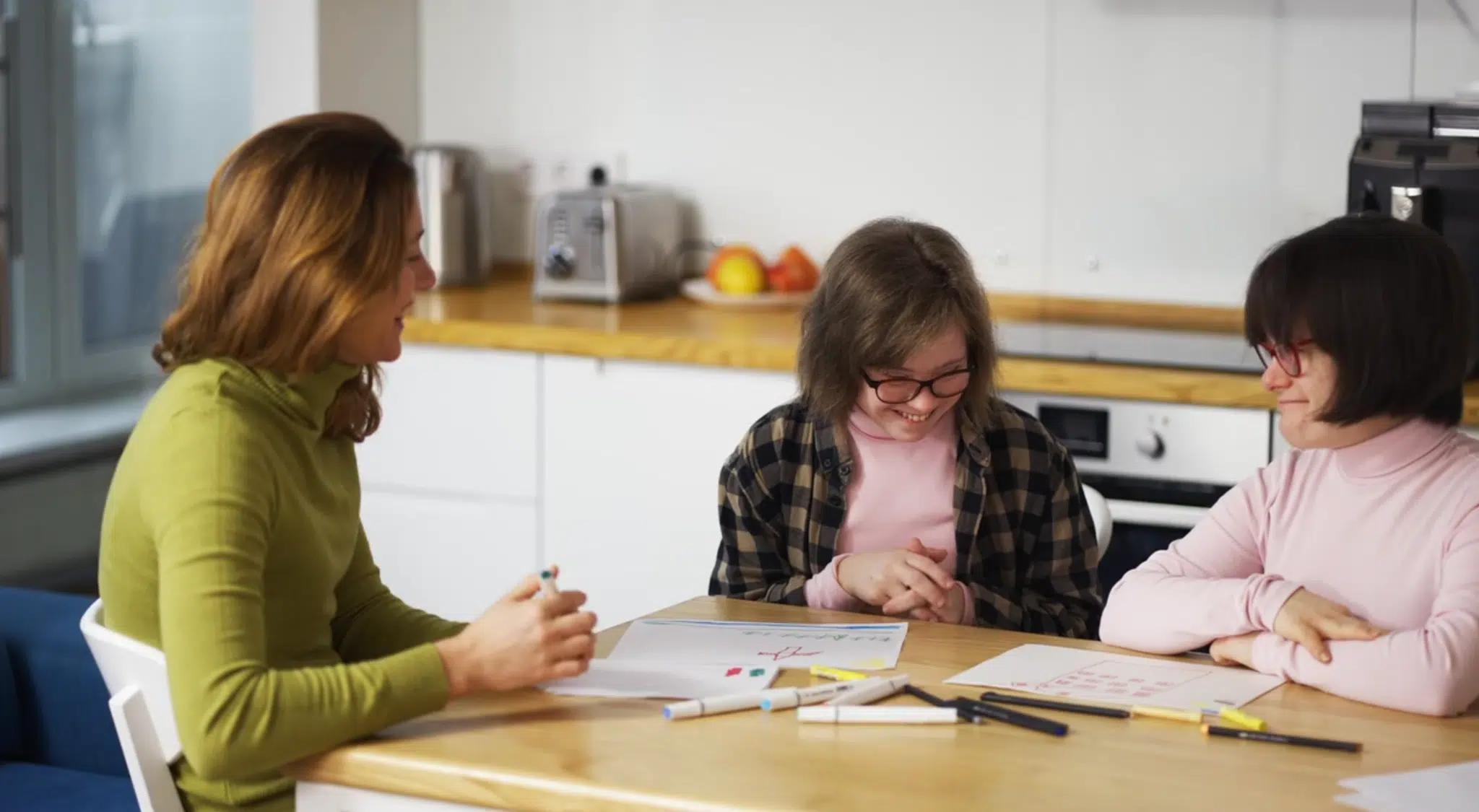 A mother drawing at the kitchen table with her two daughters