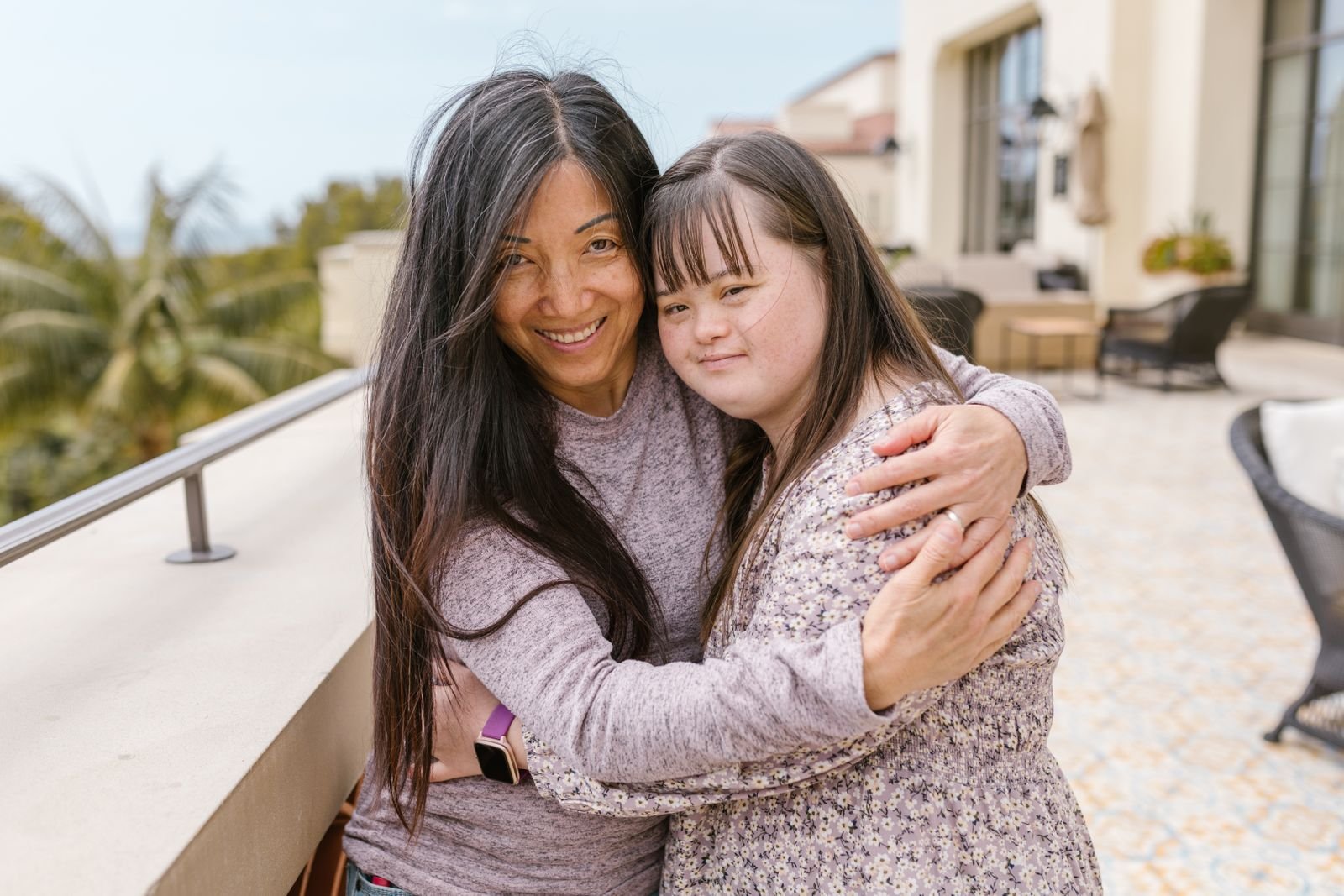 A caregiver warmly embracing an adult woman with Down syndrome at home